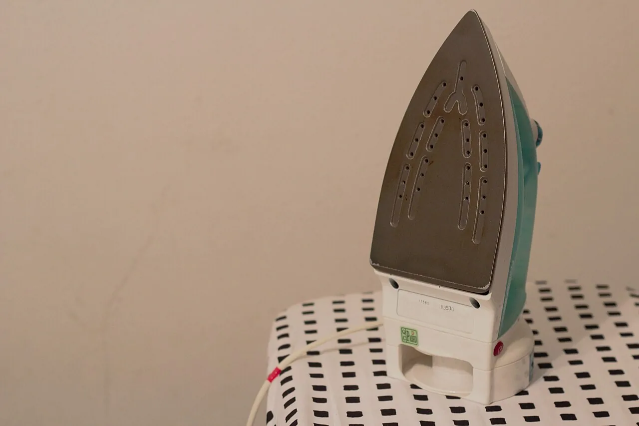 A clothes iron resting on an ironing board